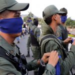 Military members place a blue arm band near the Generalisimo Francisco de Miranda Airbase in Caracas